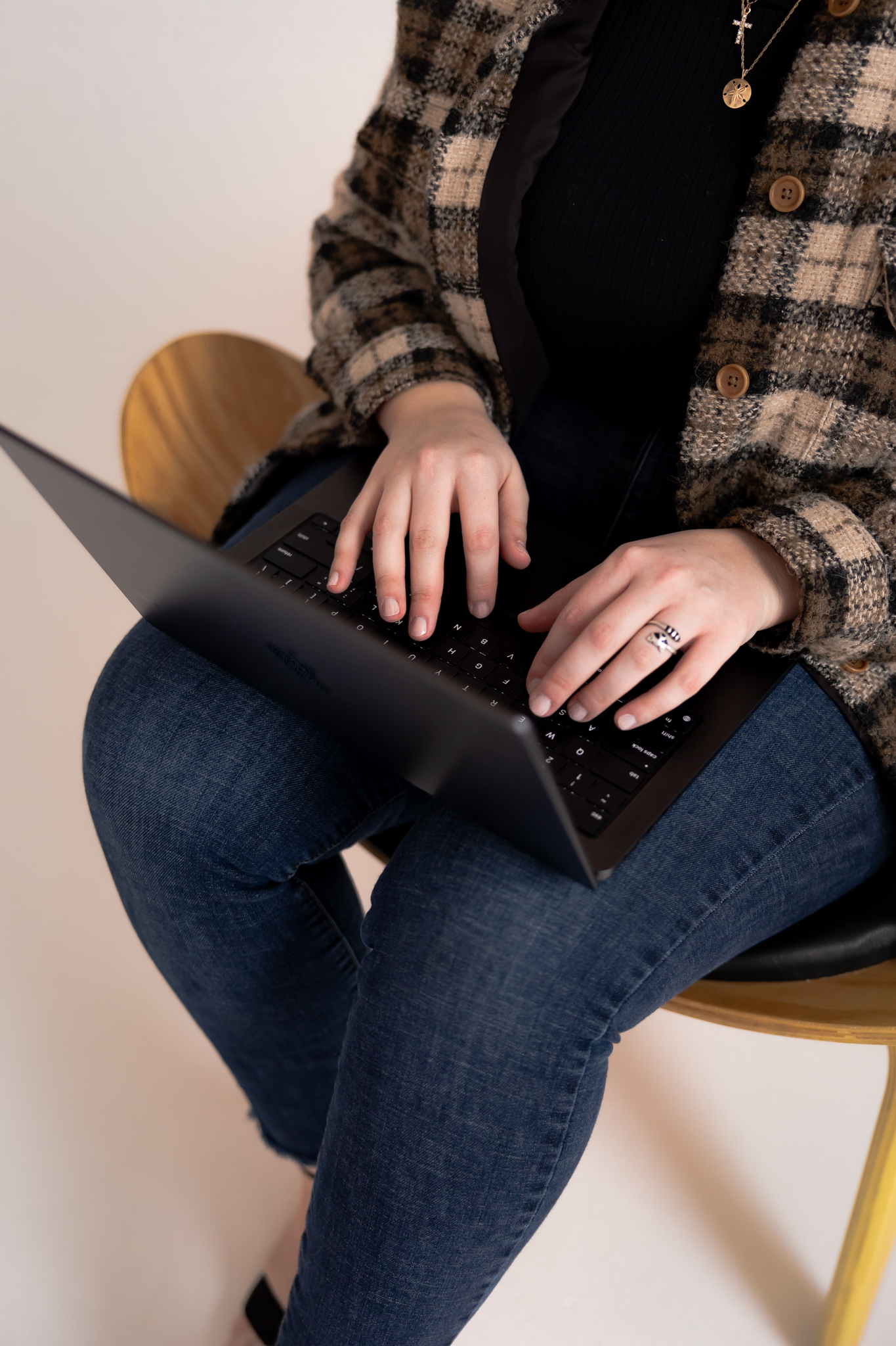 Person typing on an Apple laptop searching for frequently asked questions regarding photography services and sessions.